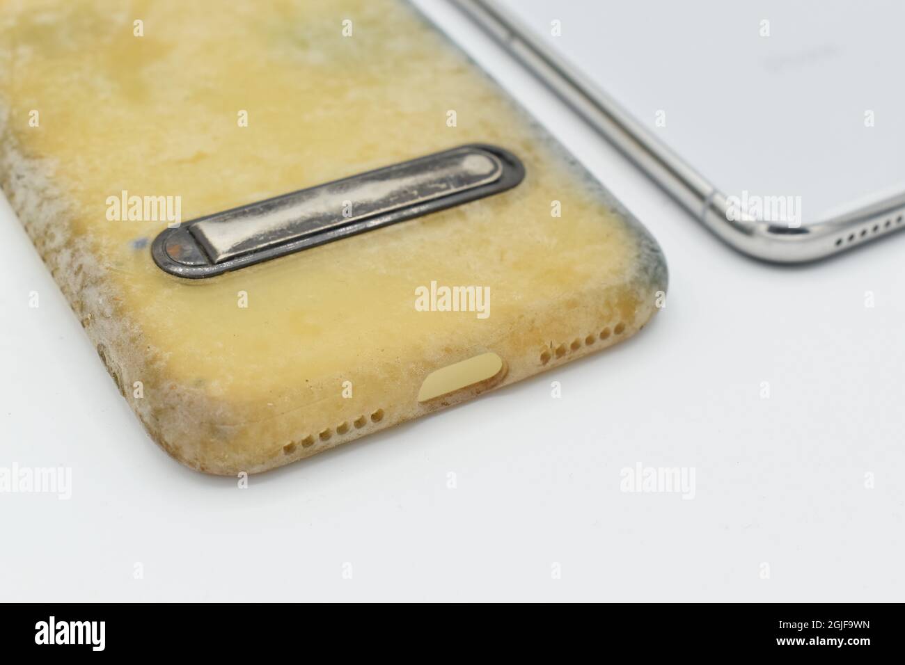 Old and dirty silicon phone case due to yellow stains and mold. Isolated on white background. Closeup view. Stock Photo