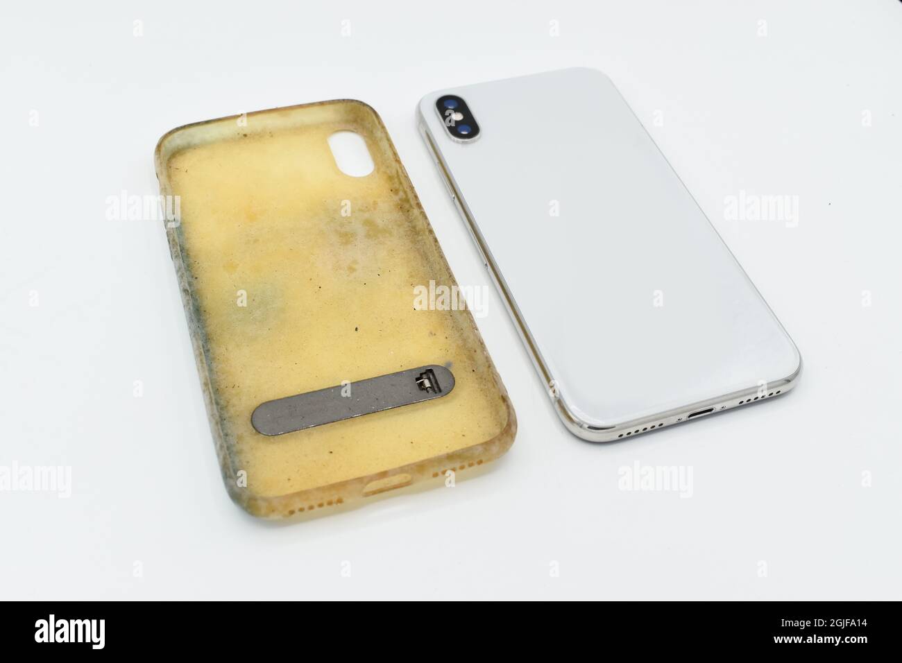 New smartphone, and old and dirty silicon phone case due to yellow stains and mold. Isolated on white background. Lateral view. Stock Photo