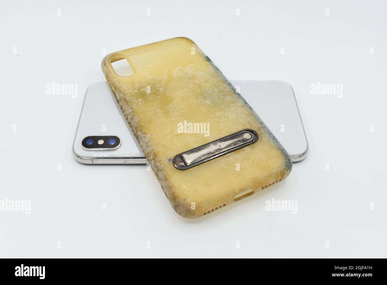 New smartphone, and old and dirty silicon phone case due to yellow stains and mold. Isolated on white background. Stock Photo