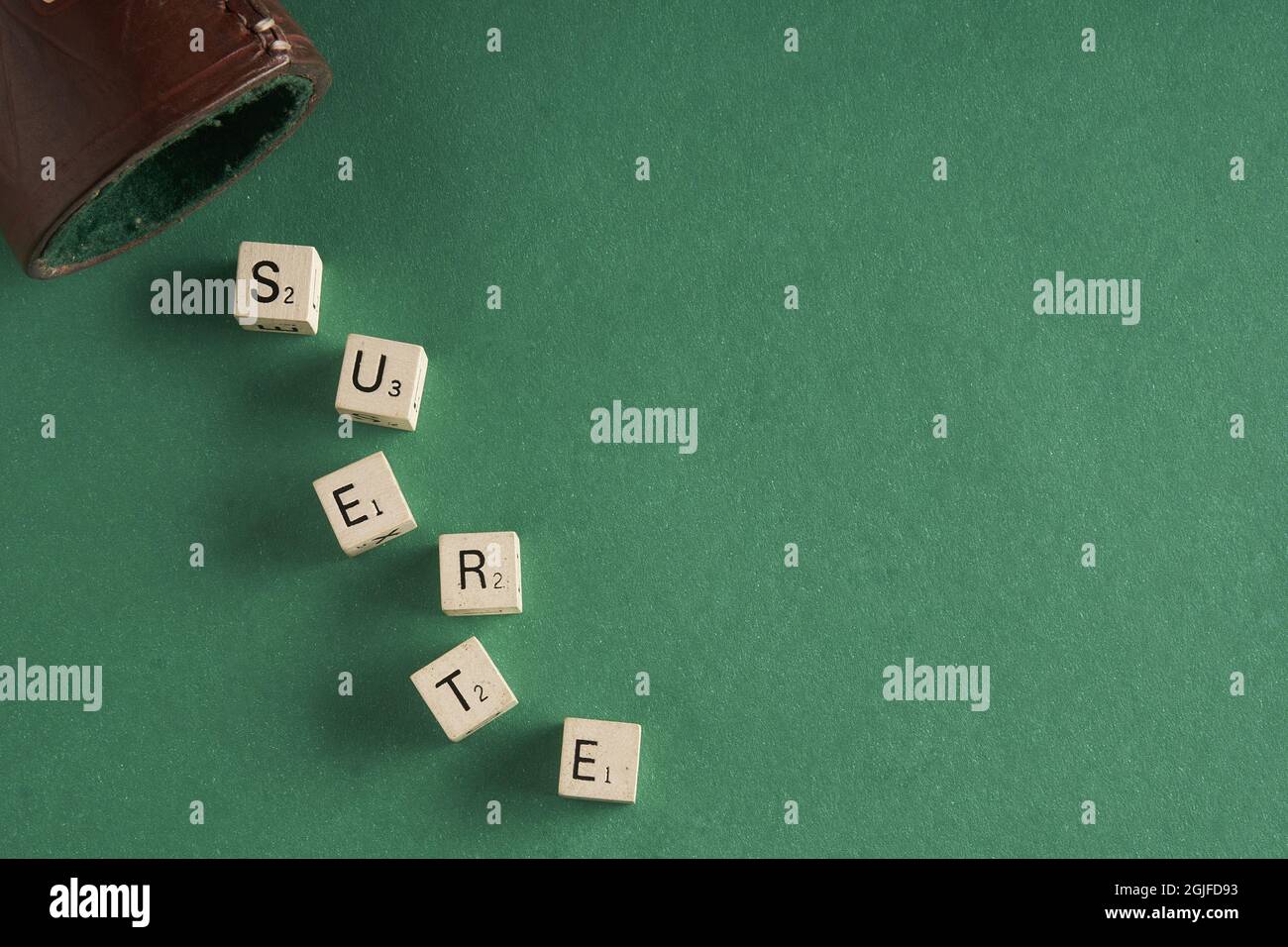 Closeup of letter dice on the green table forming the word lucky in Spanish (suerte) Stock Photo