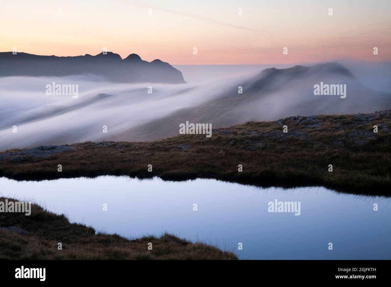 The Langdale Pikes rising above a cloud inversion, at dawn in the ...