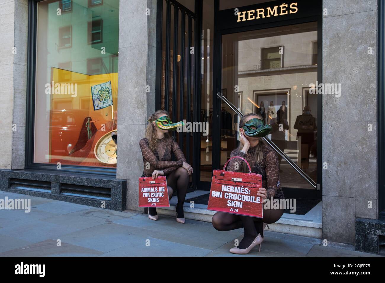 London, UK. 8th September, 2021. Two PETA supporters wearing Venetian crocodile masks pose outside the Hermès store in New Bond Street in protest against the luxury fashion house's use of exotic skins. PETA's campaign was launched following the release of video footage by The Kindness Project showing crocodiles being mutilated, electrocuted, stabbed and shot on farms in Australia with ties to Hermès and PETA are calling on the fashion brand to cease using exotic skins for their products. Credit: Mark Kerrison/Alamy Live News Stock Photo