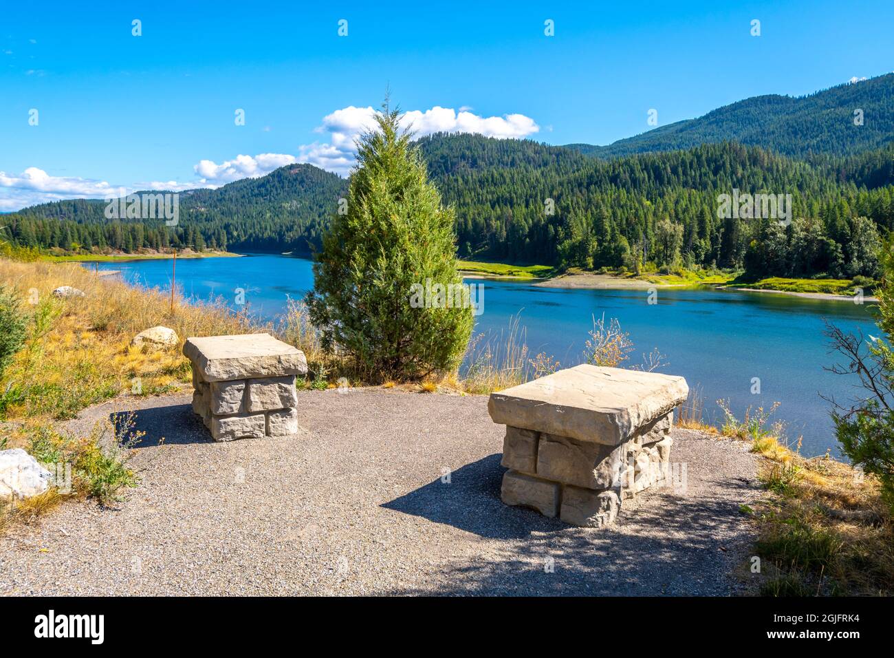 Two small stone benches in a small park rest area along the highway facing Pend Oreille River near the town of Metaline Falls, Washington, USA Stock Photo
