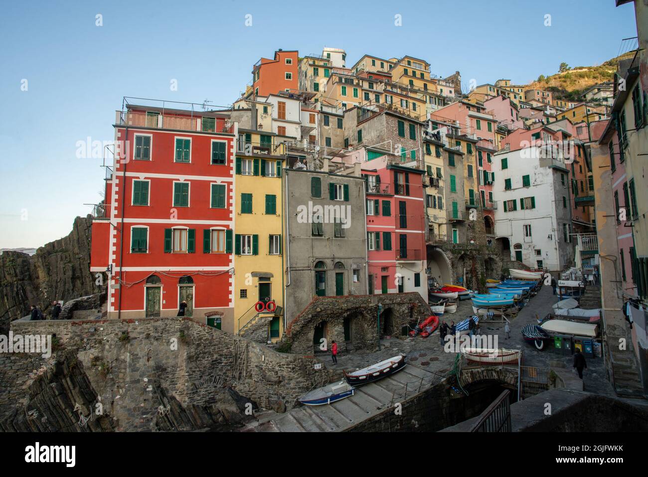 Amazing panorama of Riomaggiore town - a trip for Christmas. People ( unrecognizable persons ) walking near the water. Boats are waiting for a warmer Stock Photo