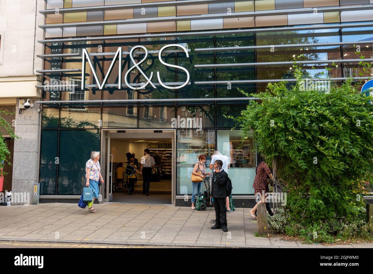Marks and Spencers main shop entrance with customers inside and shoppers walking past on a summers day in Norwich Stock Photo