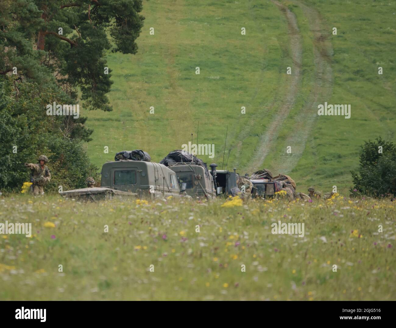 British army Land Rover Wolf 4×4 military light utility vehicle convoy with foot soldiers deployed on exercise, Salisbury Plain UK Stock Photo