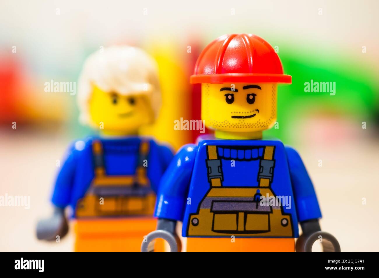 POZNAN, POLAND - Sep 09, 2021: Lego construction worker with satisfied emotion standing in front of other worker with long hair in soft focus backgrou Stock Photo