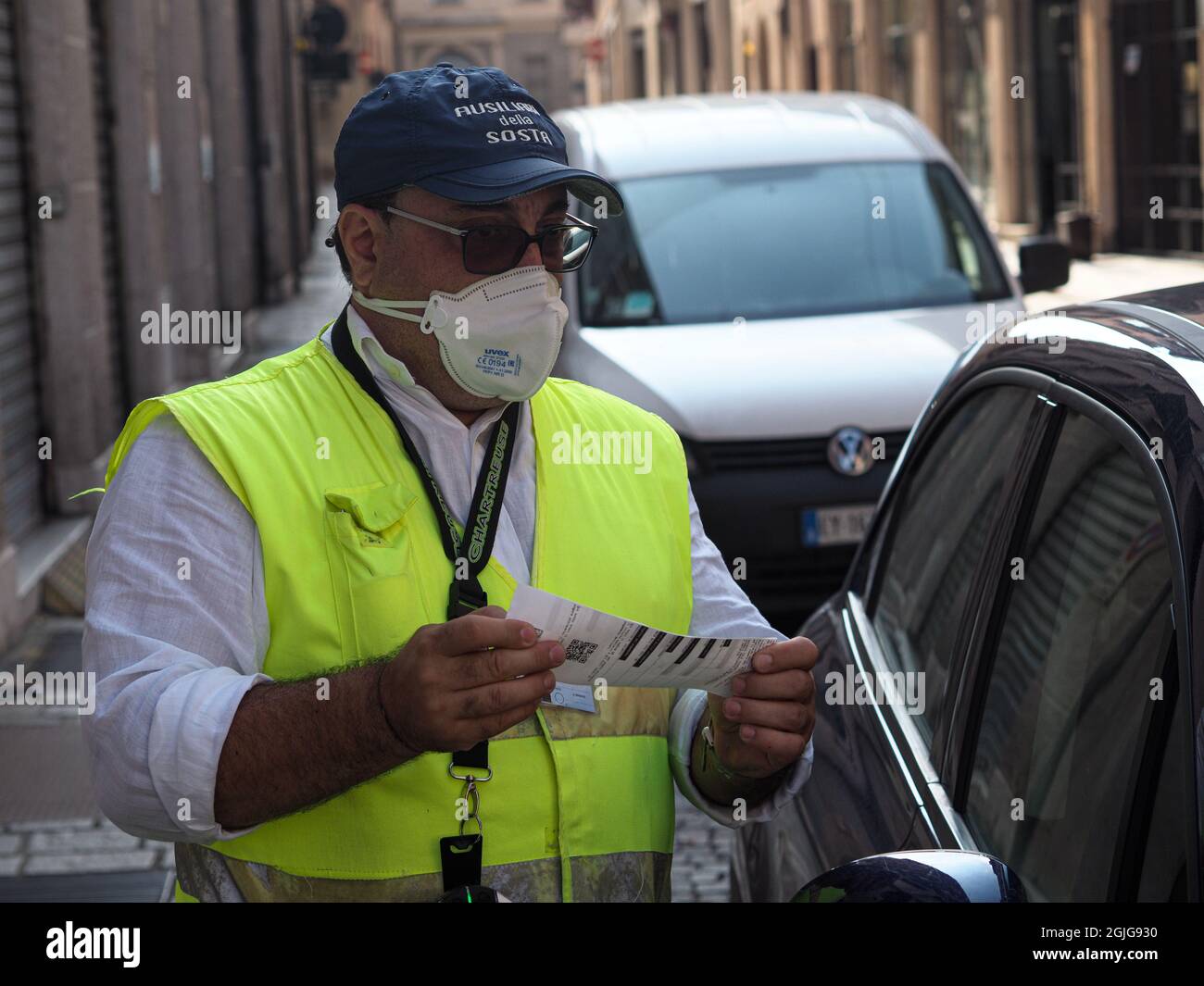 LOMBARDY, ITALY - Aug 19, 2021: A parking warden attendant from a private outsourced company issuing parking violations online printing and leaving th Stock Photo