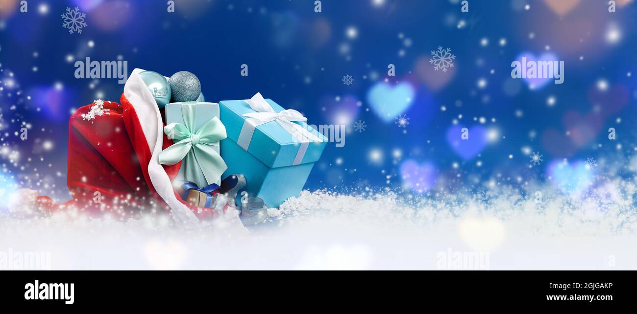 Santa Claus hat with gifts on snow against color background. Merry ...