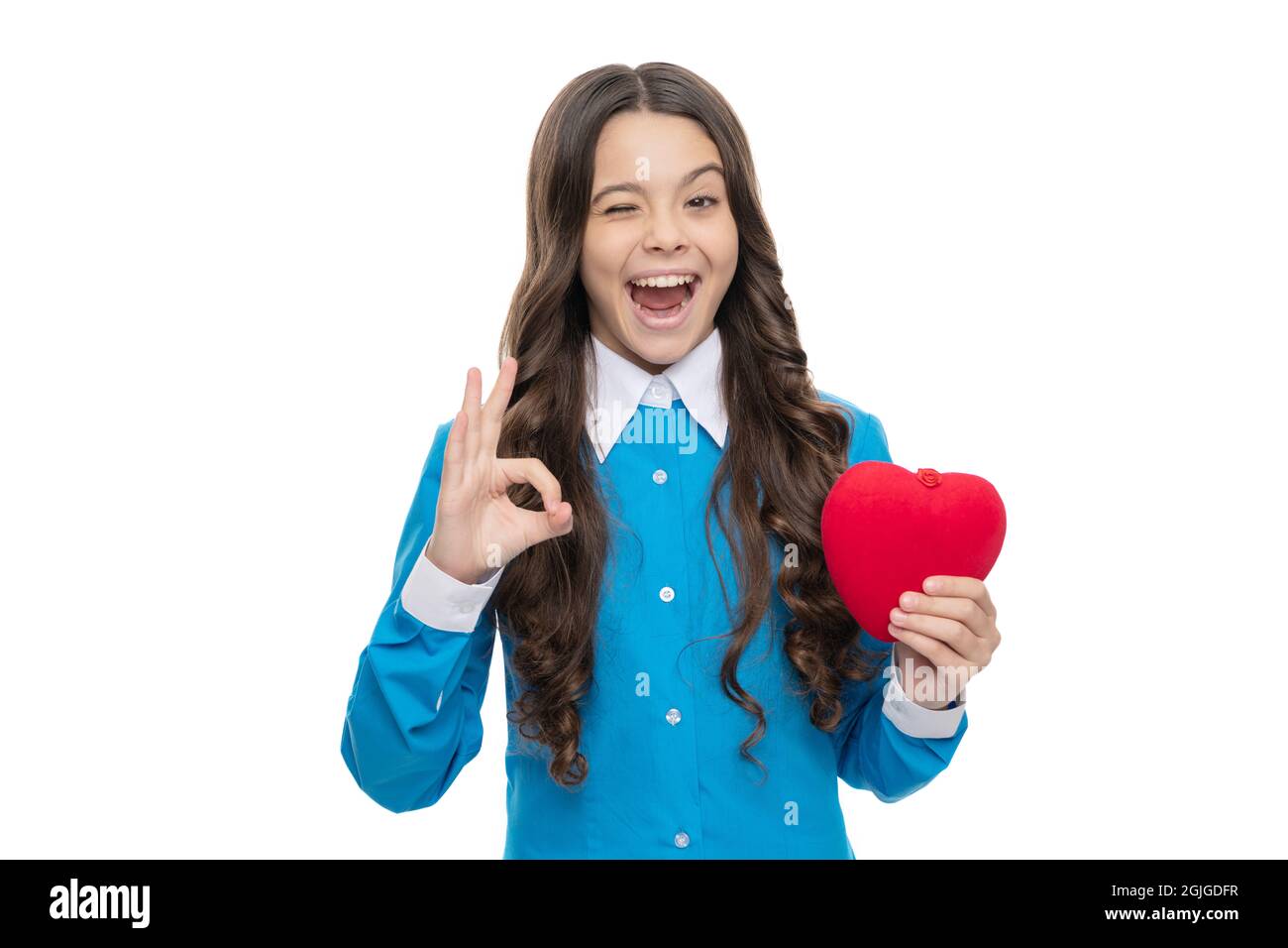 Playful girl hold red valentines heart showing OK hand gesture isolated on white, approval Stock Photo