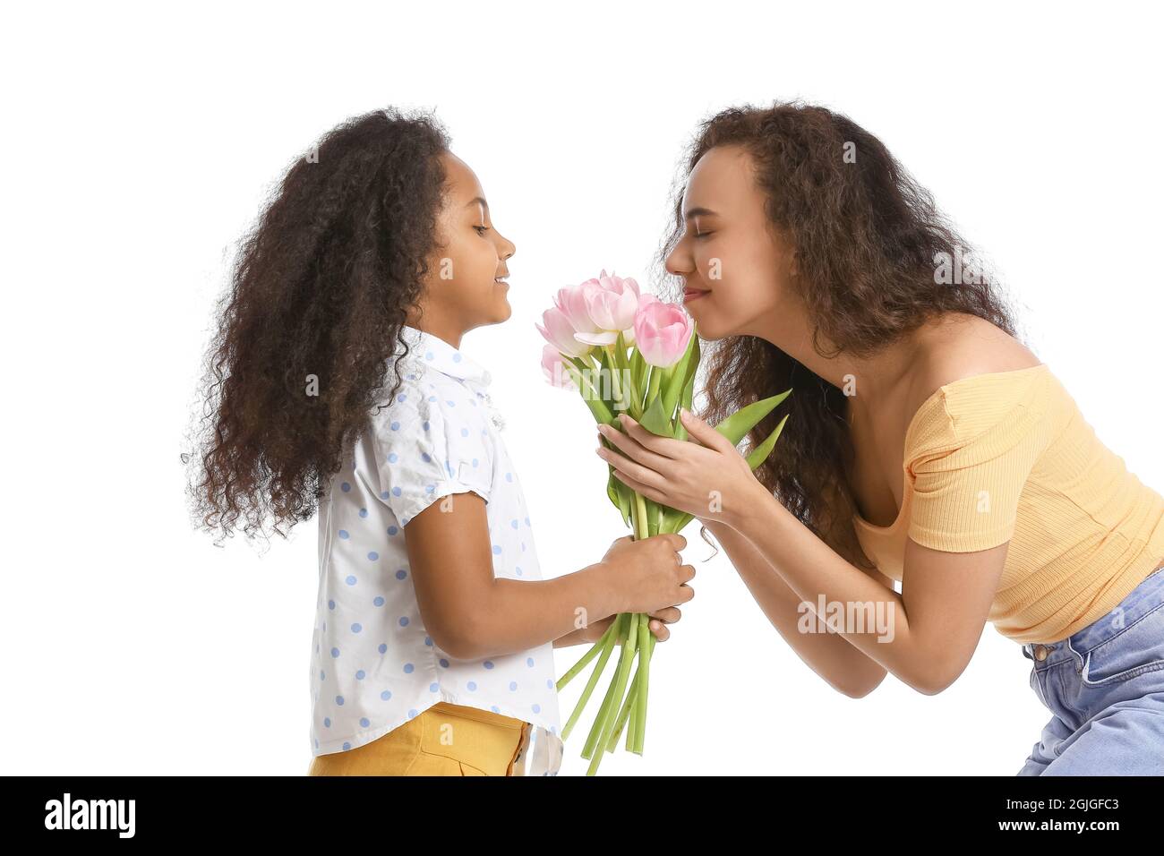 African-American little girl with her mother and bouquet of tulips on white background Stock Photo