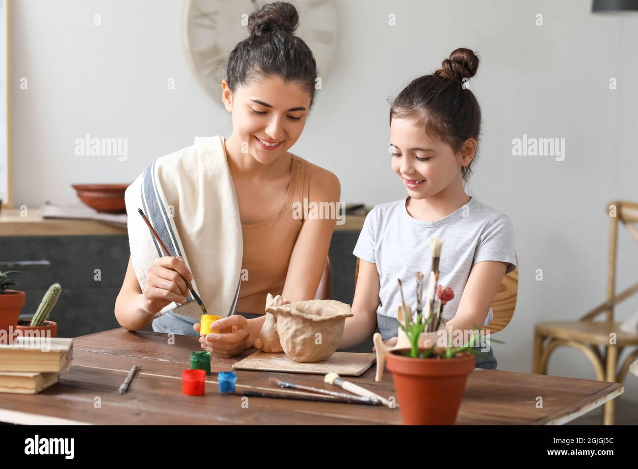 Little girl with her mother painting ceramic pot at home Stock Photo ...