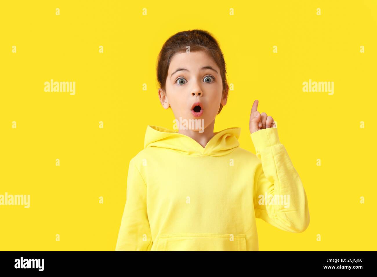 Cute little girl with raised index finger on color background Stock ...