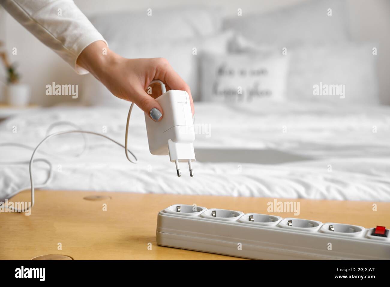 Woman putting plug into extension cord in bedroom Stock Photo Alamy