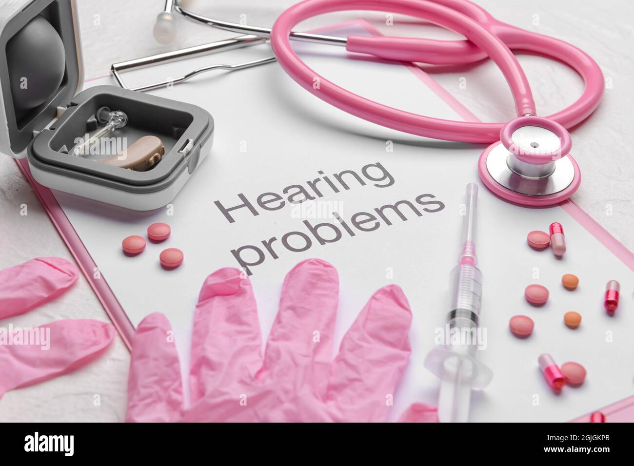 Clipboard with text HEARING PROBLEMS, stethoscope and gloves on white background Stock Photo