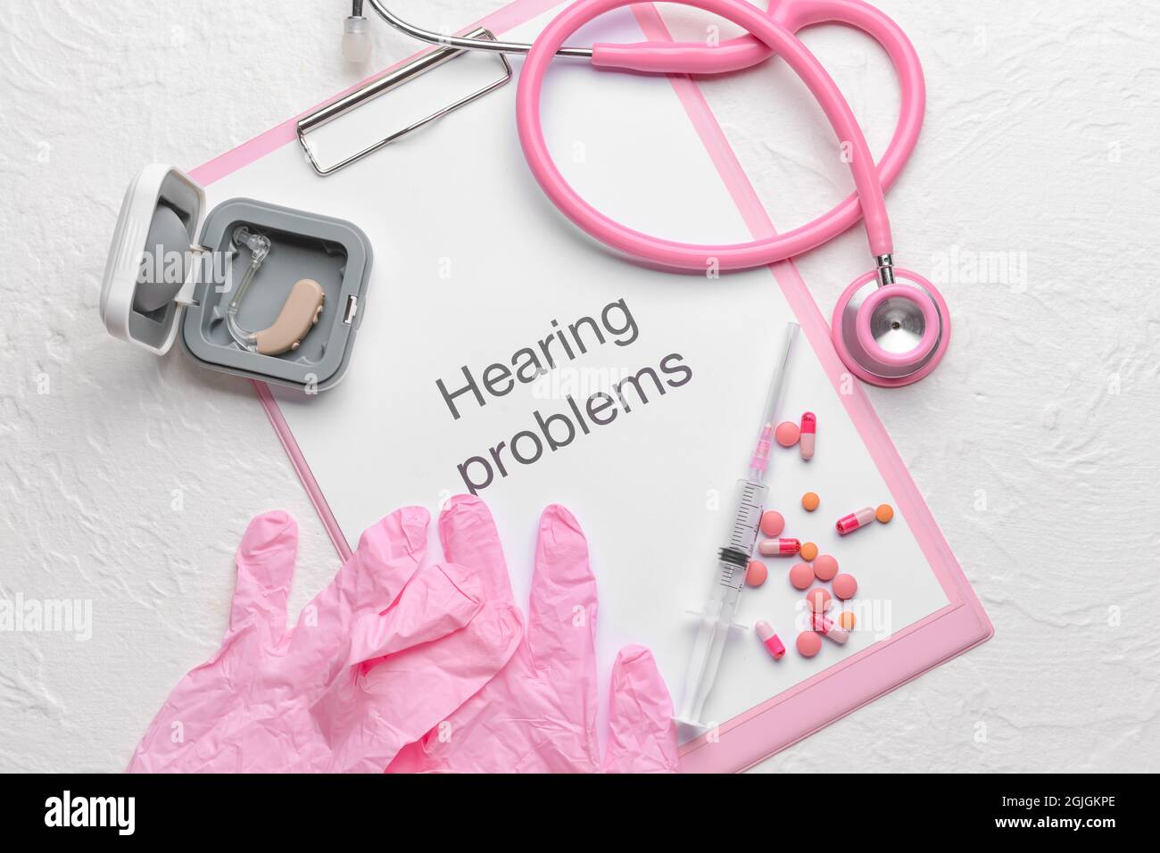 Clipboard with text HEARING PROBLEMS, stethoscope and gloves on white background Stock Photo