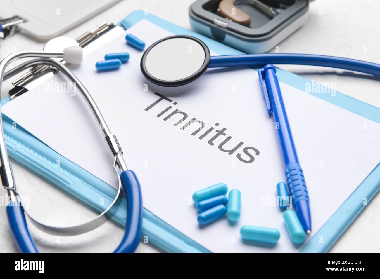 Clipboard with word TINNITUS, stethoscope and pills on white background Stock Photo