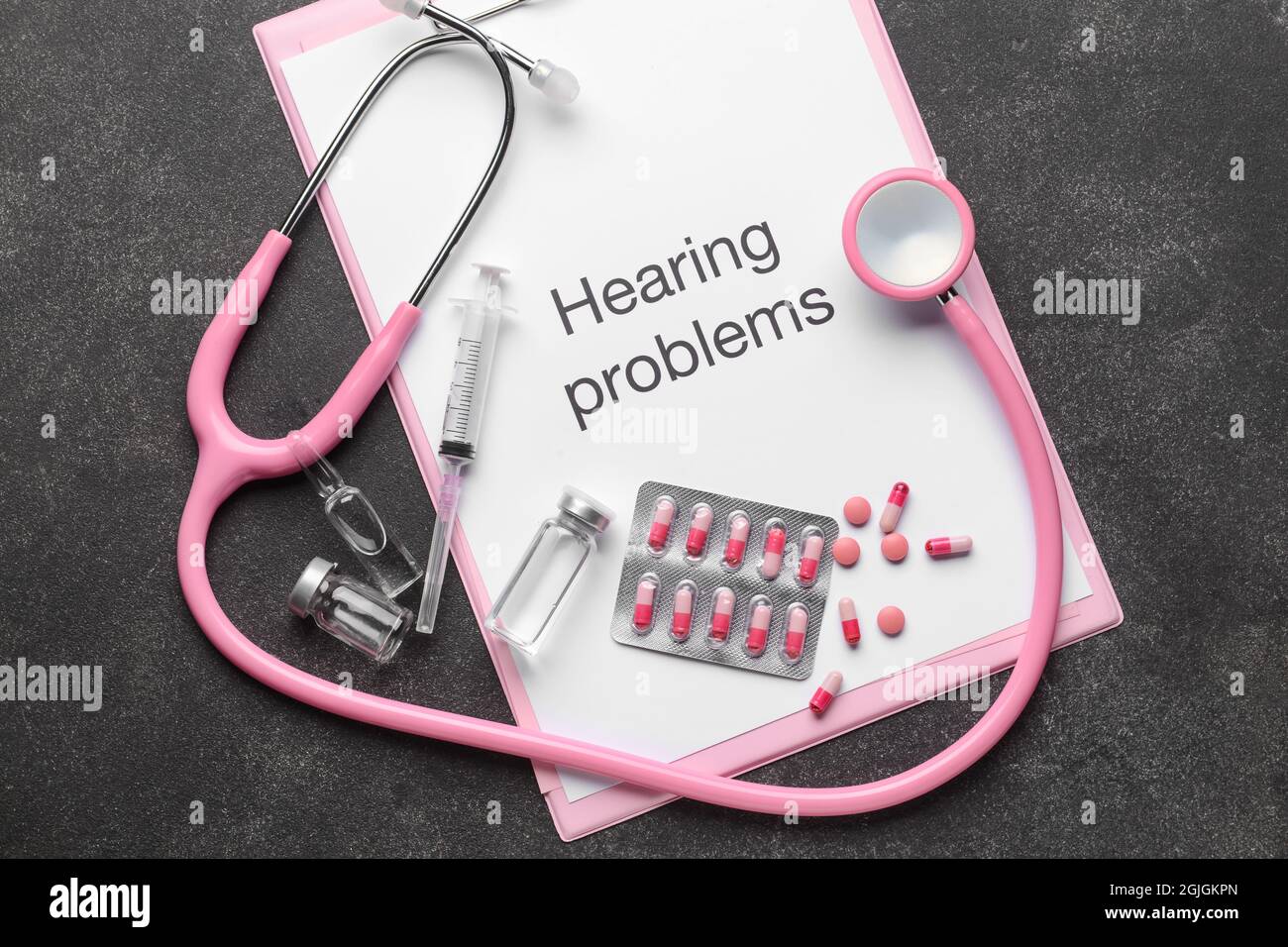 Clipboard with text HEARING PROBLEMS, stethoscope and pills on dark background Stock Photo