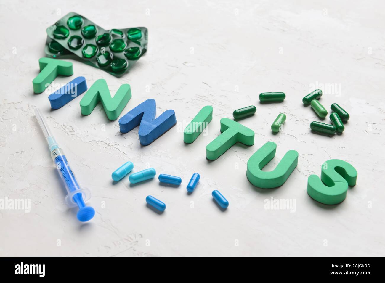 Word TINNITUS with pills and syringe on white background Stock Photo