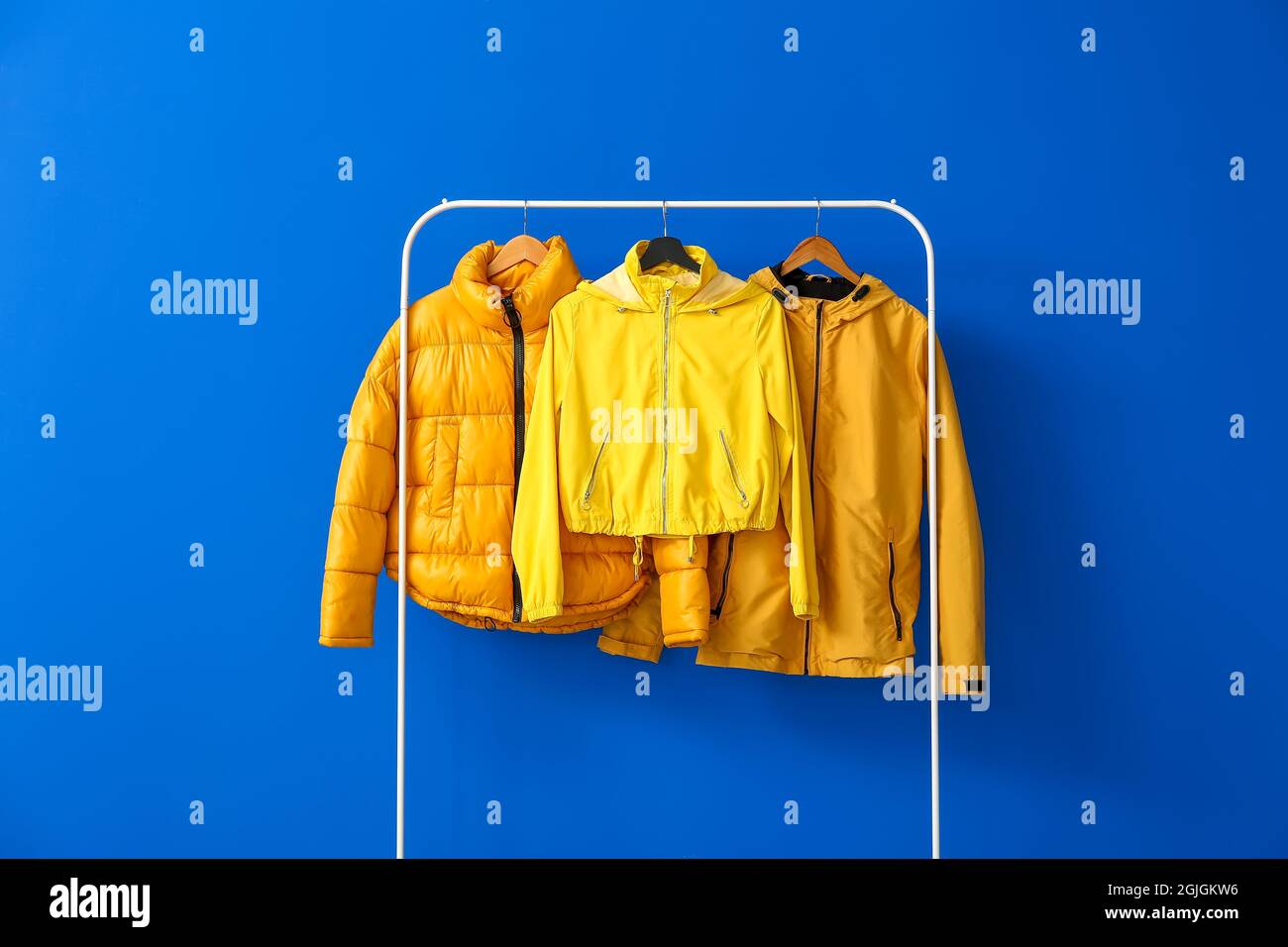 Rack with bright jackets on color background Stock Photo