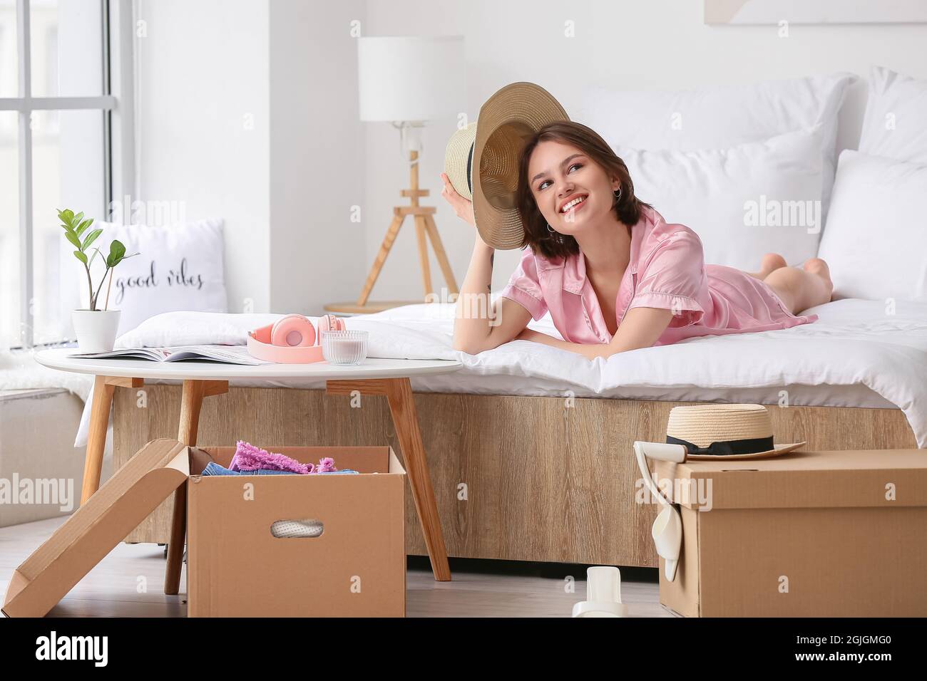 Young woman with wardrobe boxes in bedroom Stock Photo