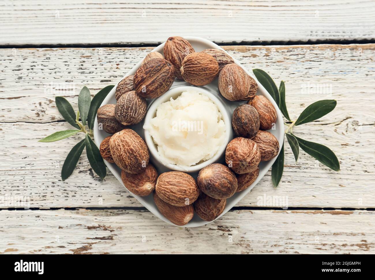 Bowl with shea butter and nuts on light wooden background Stock Photo ...