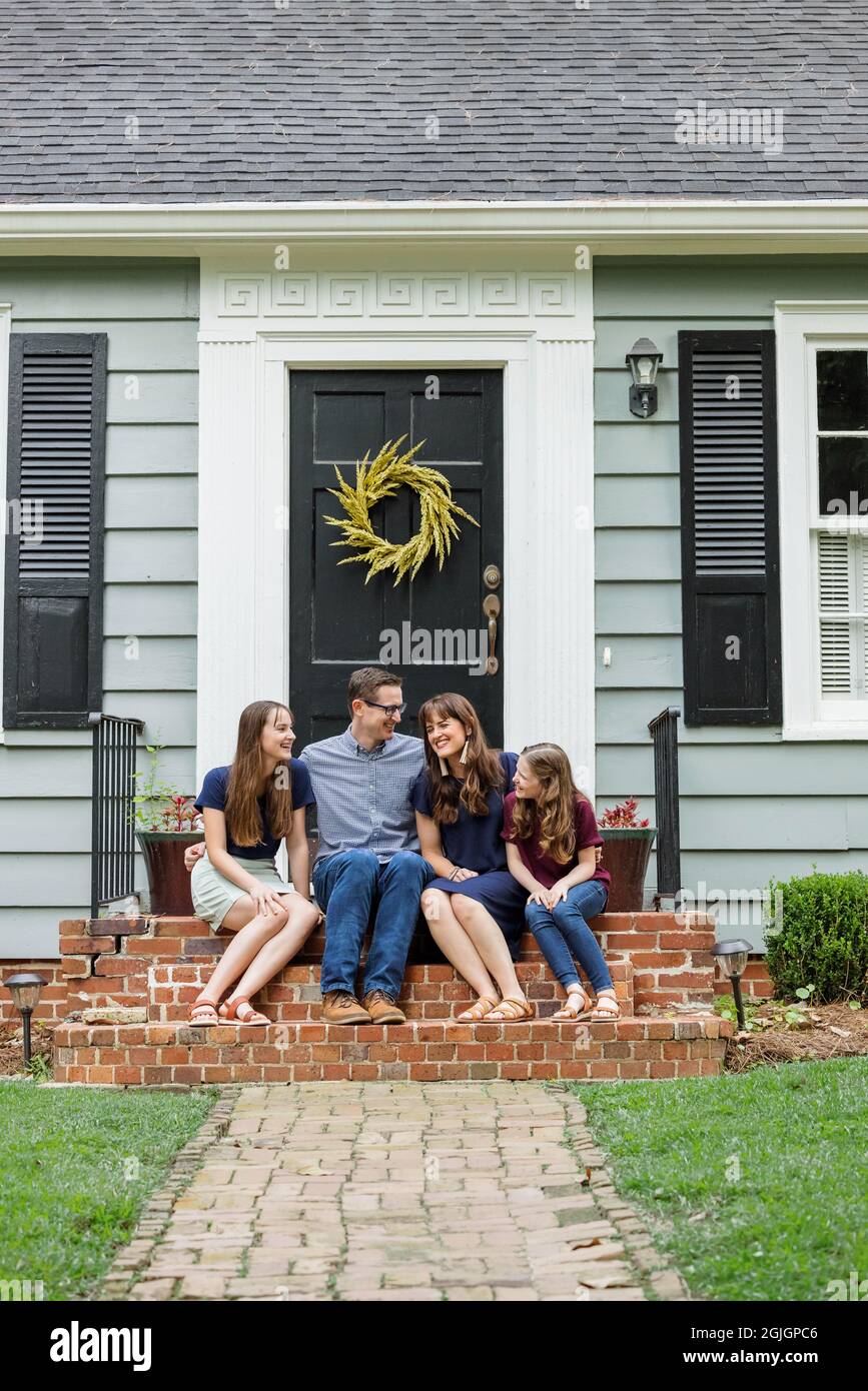 A family with a mother, father, and two daughters sitting outside on