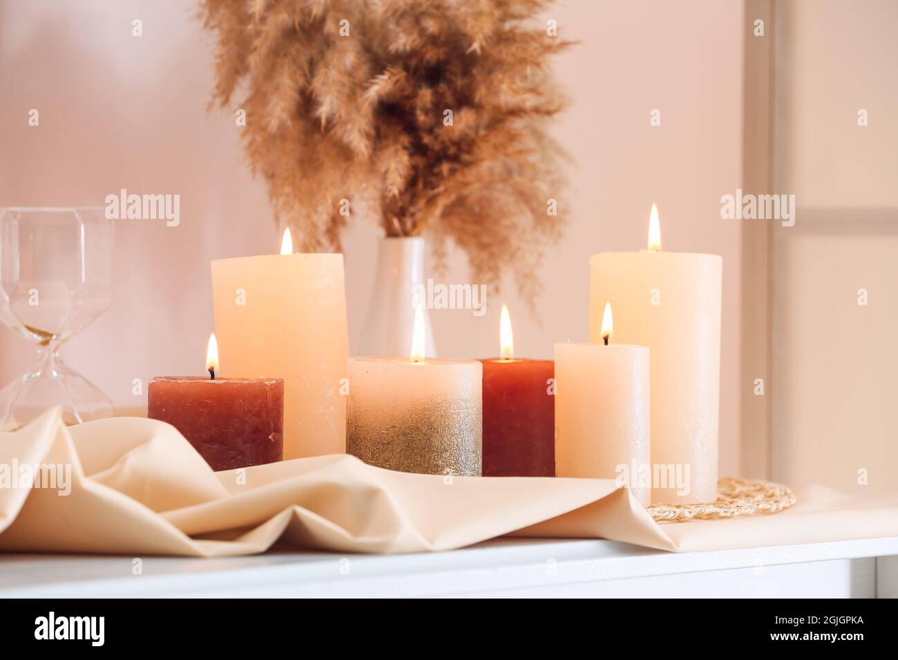 Beautiful burning candles on shelf in light room Stock Photo Alamy