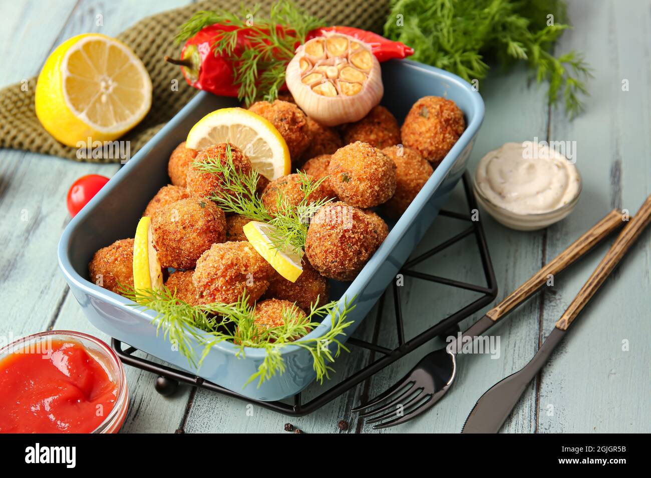 Cod Cutlets Baking dish with tasty cod cutlets and sauces on color wooden ...