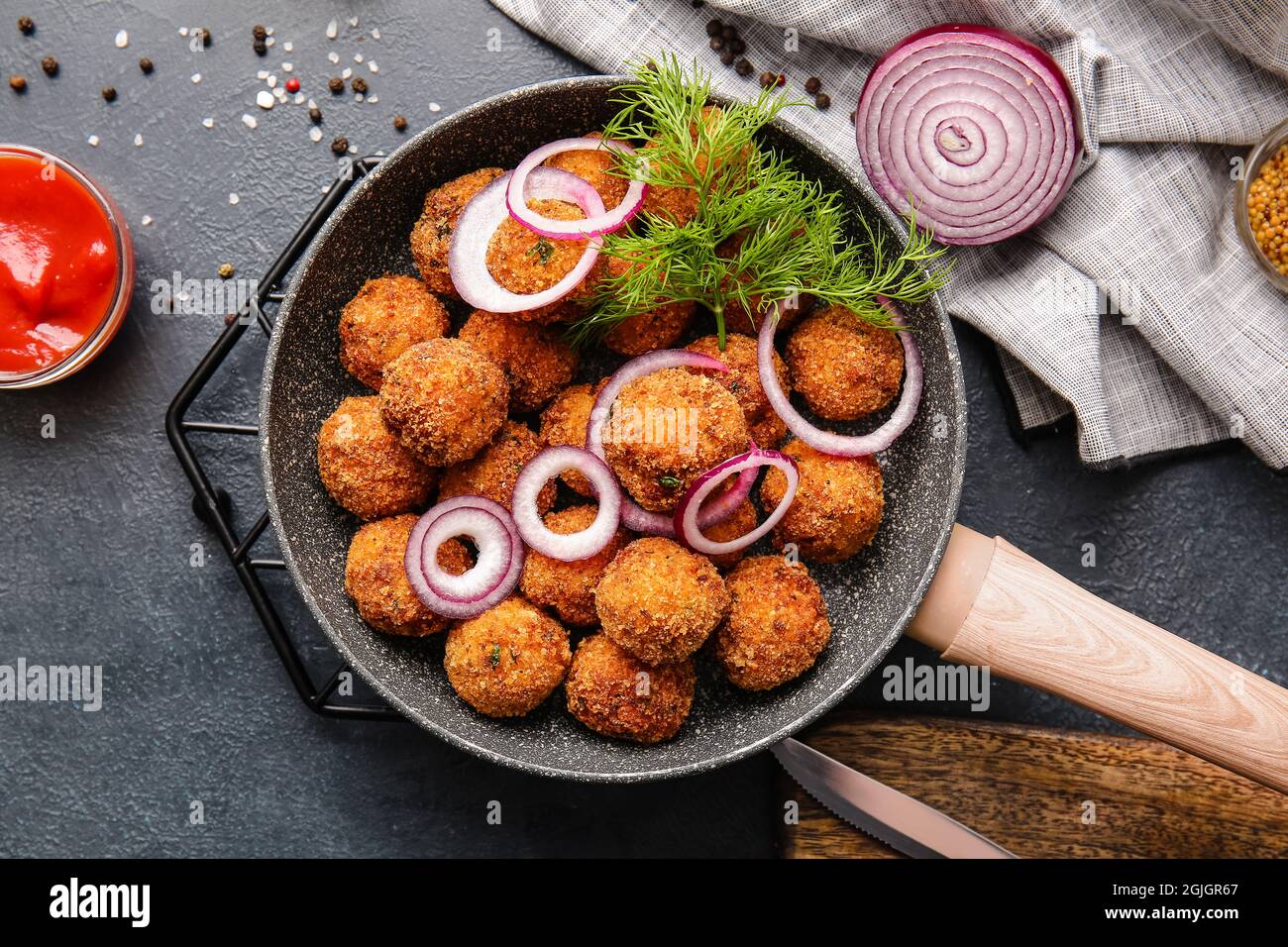 Frying pan with tasty cod cutlets and sauce on dark background Stock Photo