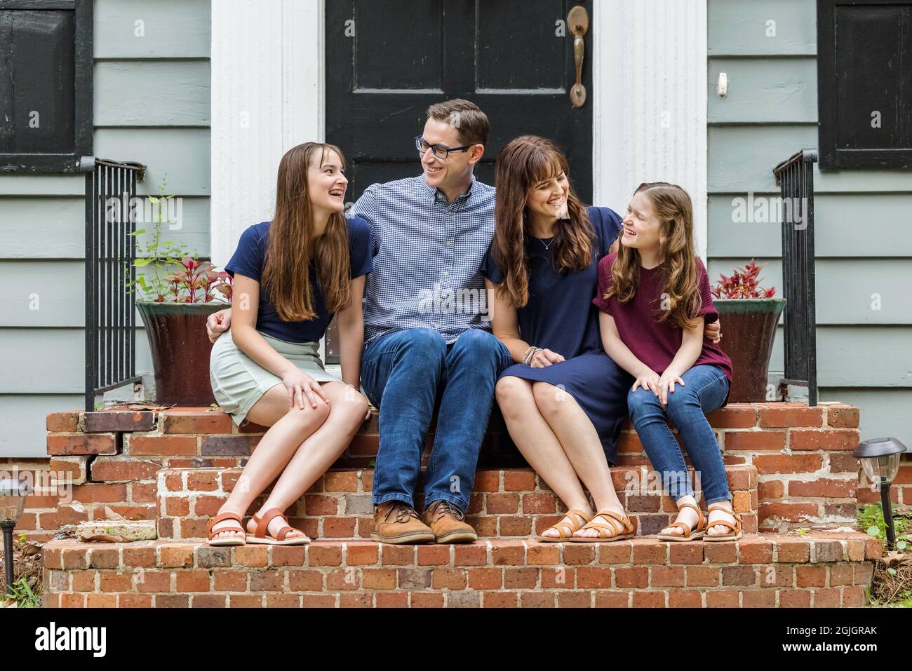 A family with a mother, father, and two daughters sitting outside on