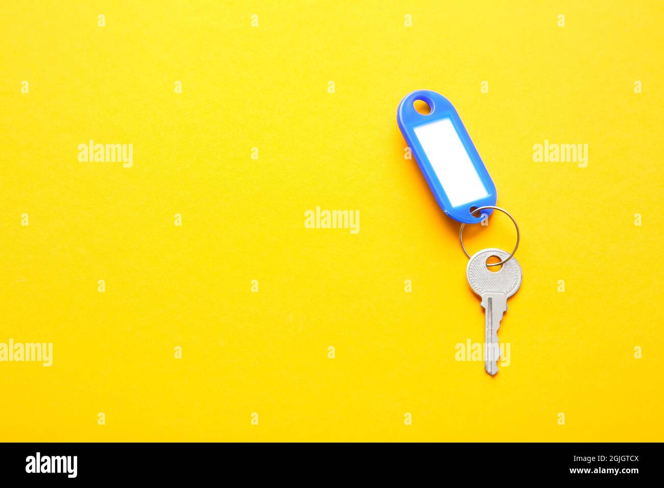 Plastic tag with key on color background Stock Photo
