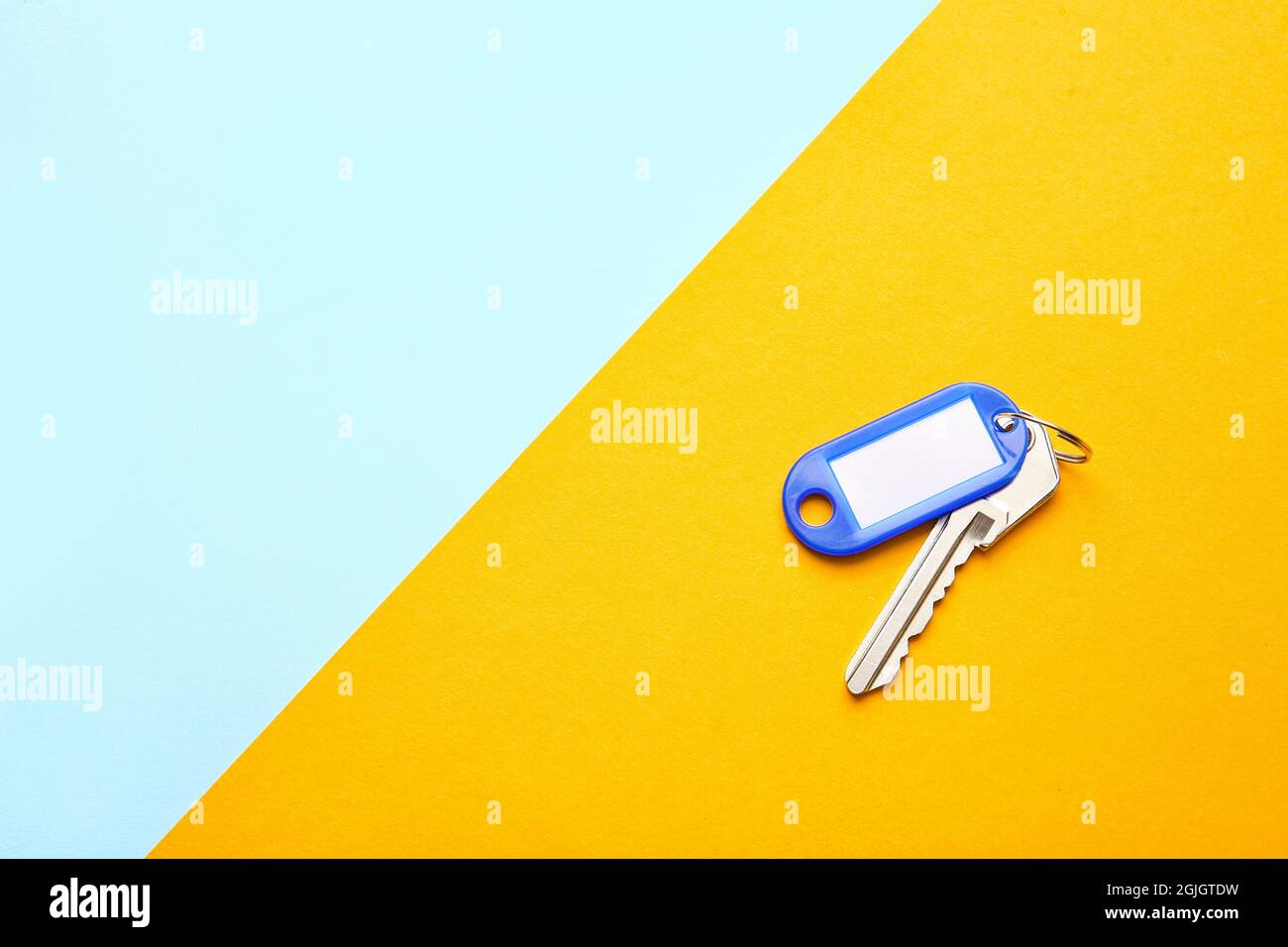Plastic tag with key on color background Stock Photo