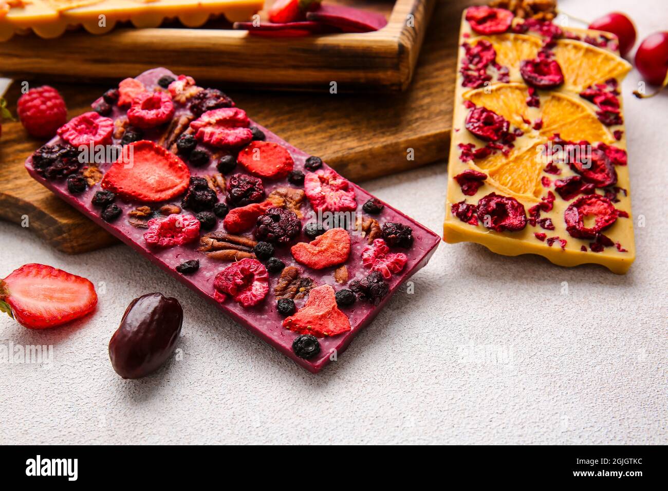Handmade chocolate bars with fruits, berries and nuts on light ...