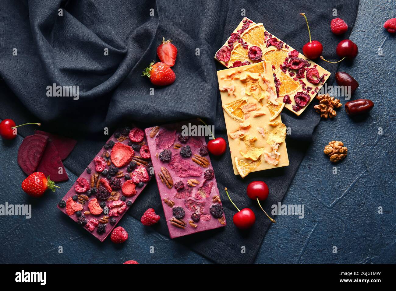 Handmade chocolate bars with fruits, berries and nuts on dark ...