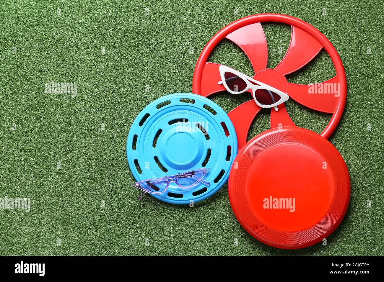 Different frisbee disks and sunglasses on color background Stock Photo