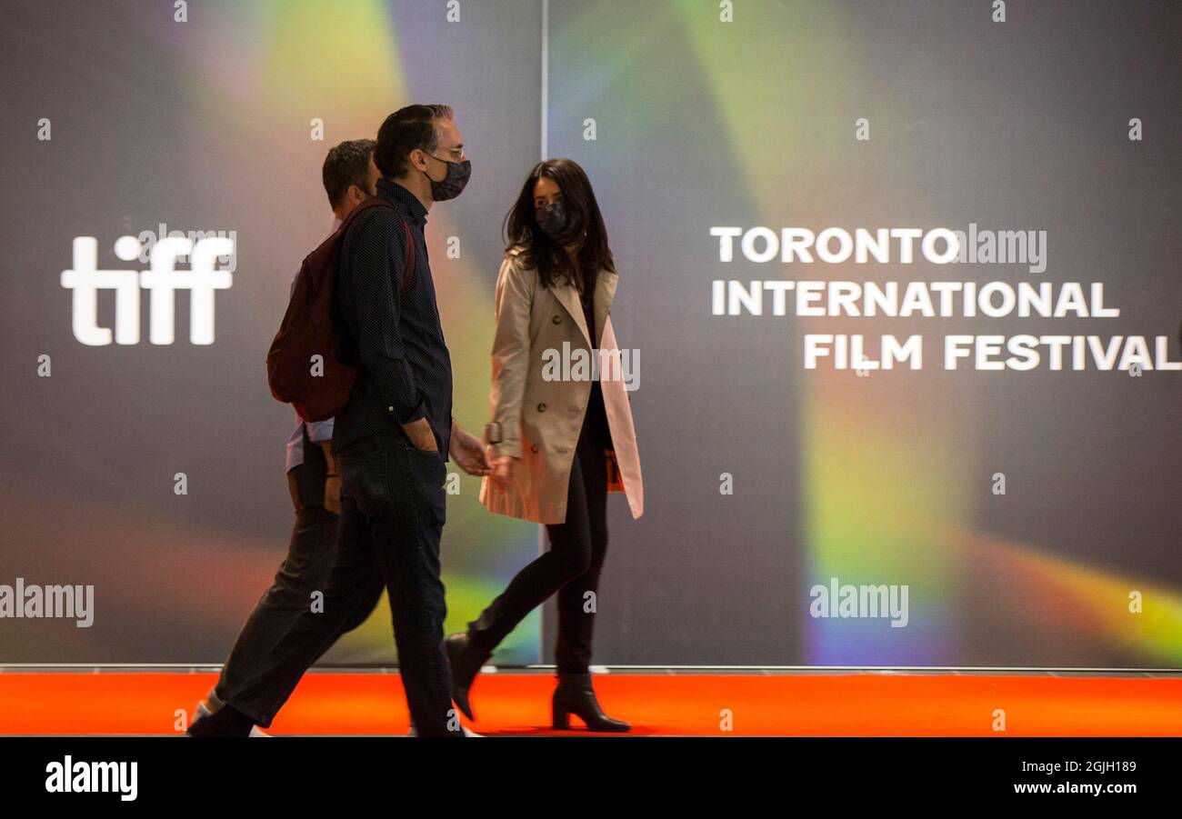 Toronto, Canada. 9th Sep, 2021. People wearing face masks walk past a wall with the TIFF logo at the TIFF Bell Lightbox headquarters of the 2021 Toronto International Film Festival (TIFF) in Toronto, Canada, on Sept. 9, 2021. The TIFF kicked off here on Thursday, offering indoor screenings, drive-ins, open-air cinemas and online. Credit: Zou Zheng/Xinhua/Alamy Live News Stock Photo