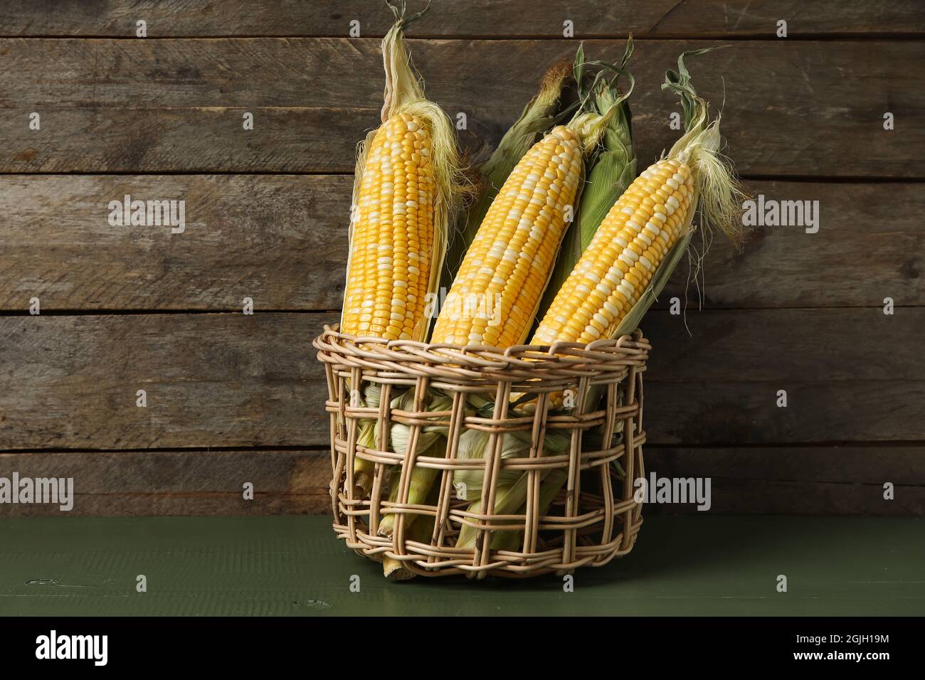 Wicker basket with fresh corn cobs on wooden background Stock Photo - Alamy