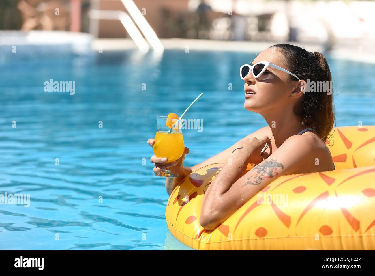 Young woman with cocktail in swimming pool Stock Photo - Alamy
