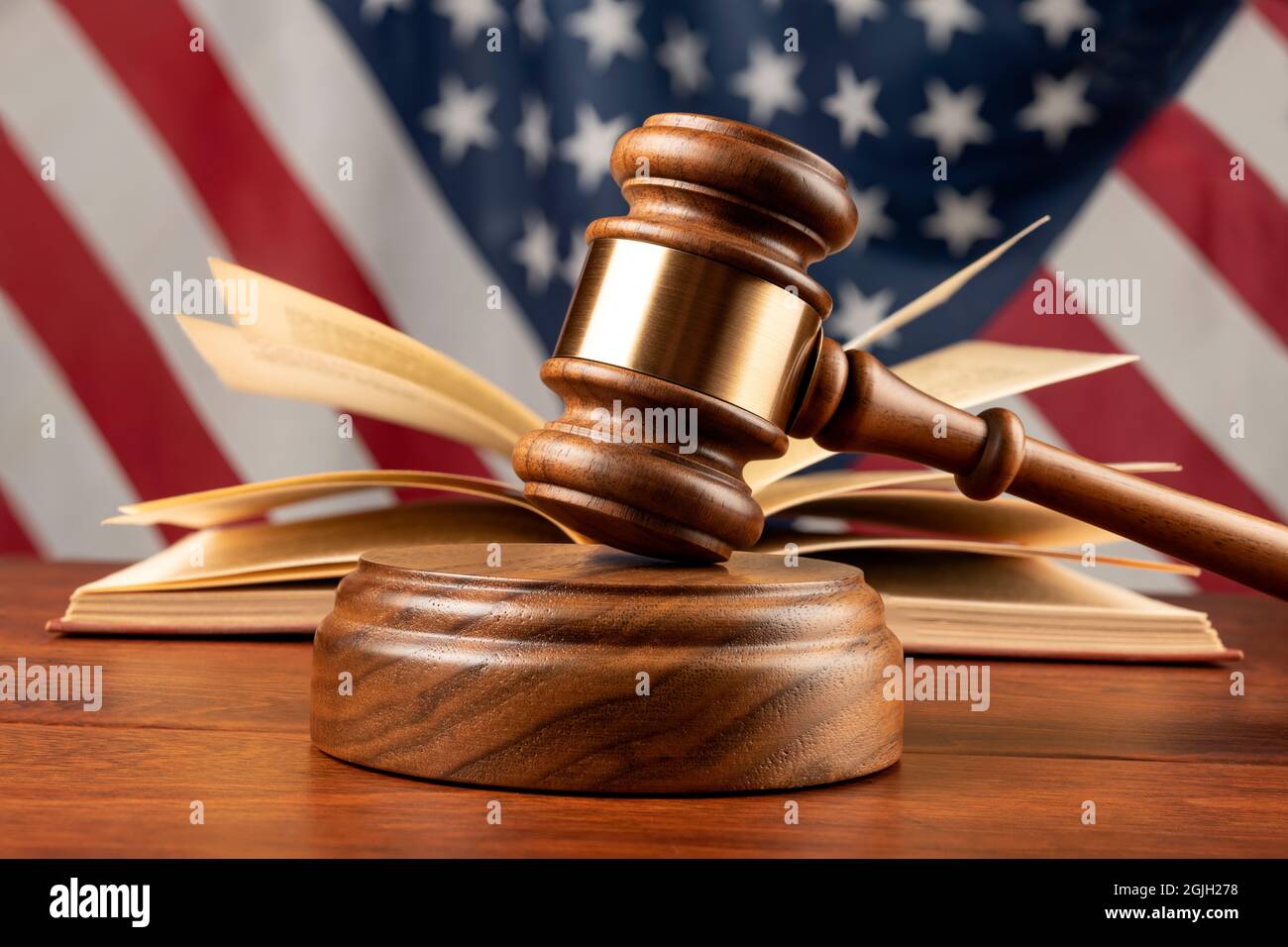 A gavel and wooden block rest atop a judge's desk with a book and