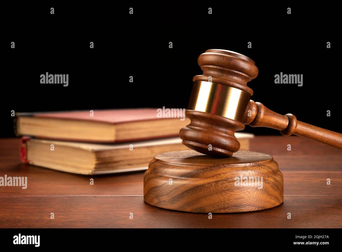 A gavel sits in front of a law book to infer research is needed for a defense and to build a case. Stock Photo