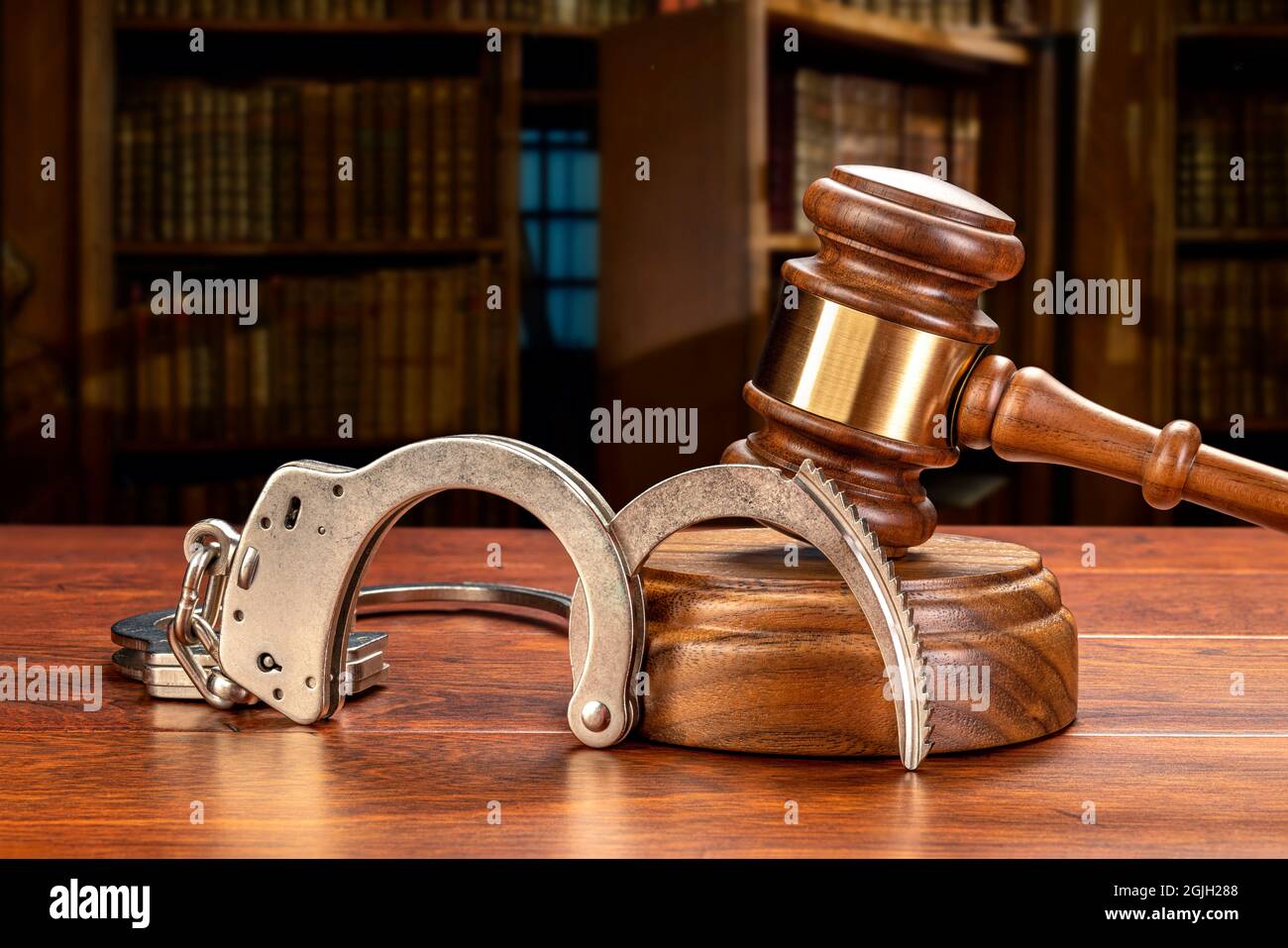 A pair of handcuffs rests against a judge's gavel and block in a judge's law chamber.  For inferences regarding public safety, crime, law and punishme Stock Photo