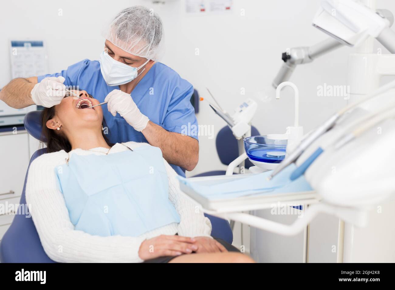 Dentist man examining a latin female patient teeth Stock Photo Alamy