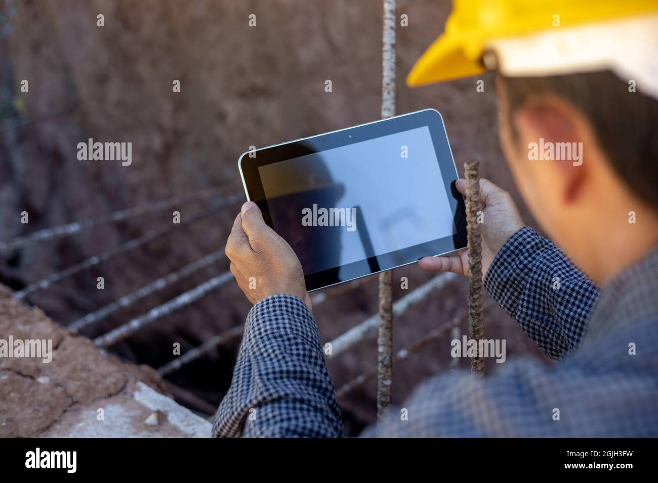 architect or civil engineer with hardhat on construction site checking schedule on tablet computer Stock Photo