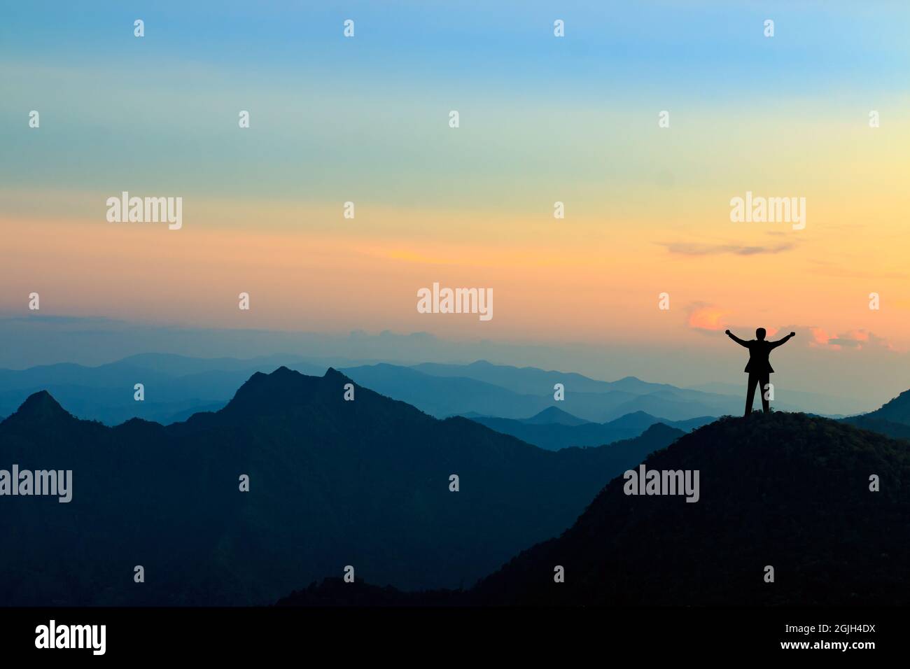 silhouette of businessman on mountain top over sunset sky background ...