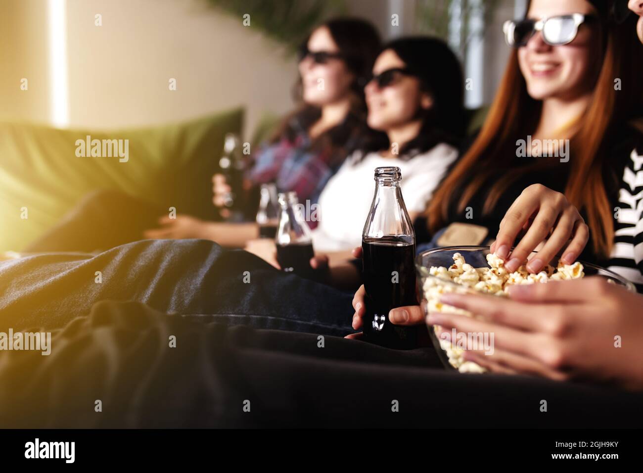 Group of people are watching a movie. Friend girls eat popcorn and drink soda Stock Photo