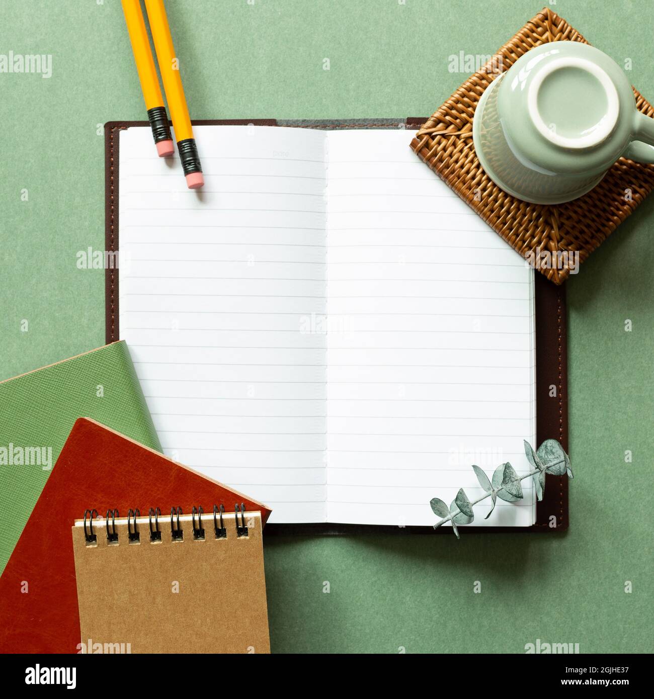 Open notebook, coffee cup, pencil on green background. top view, copy space. workspace, study concept Stock Photo
