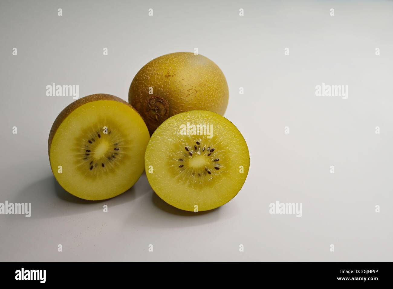 A Golden Kiwifruit or Chinese gooseberry (Actinidia chinensis) cut crosswise and a whole berry on white background Stock Photo