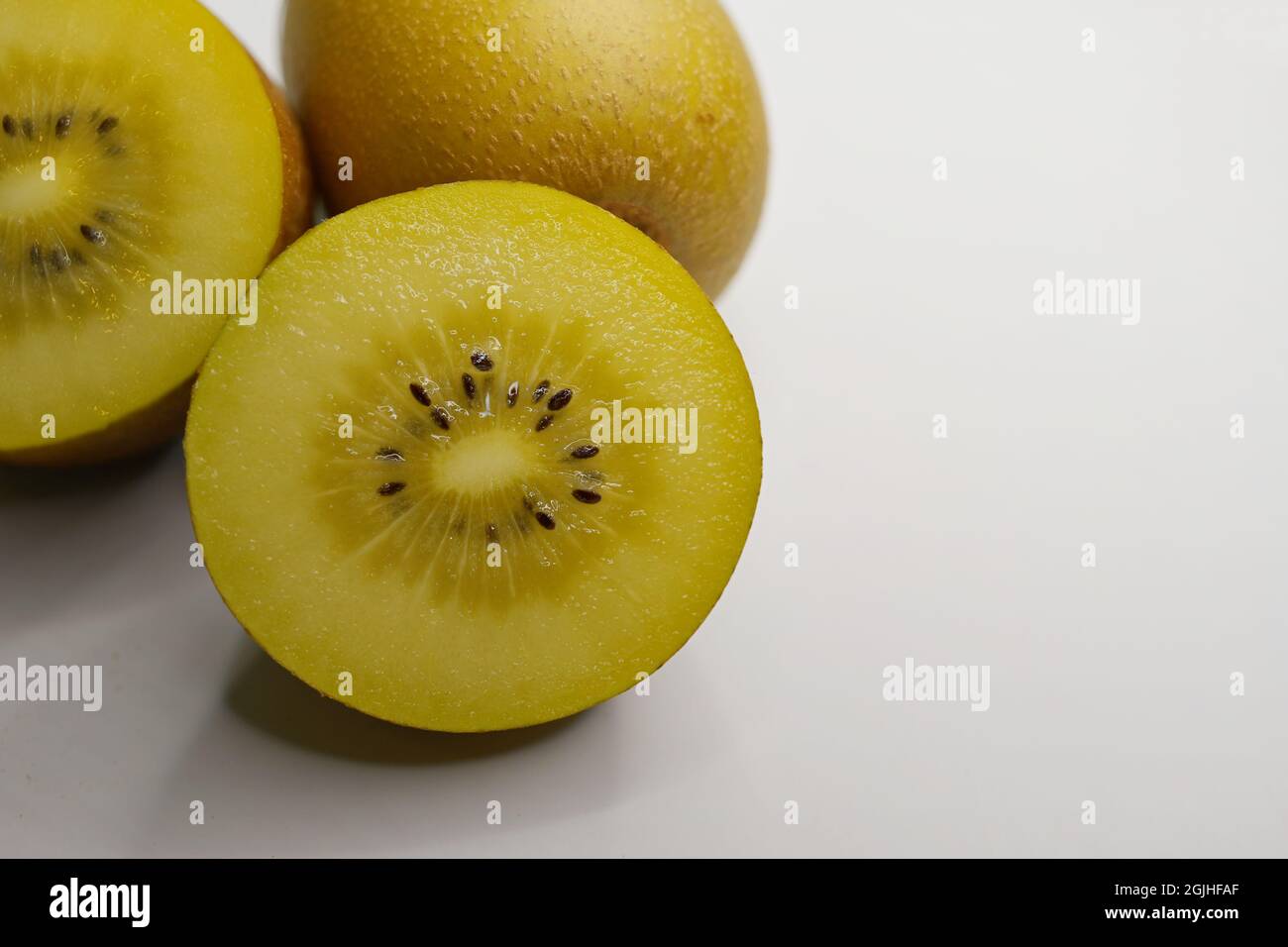 A Golden Kiwifruit or Chinese gooseberry (Actinidia chinensis) cut crosswise and a whole berry on white background Stock Photo