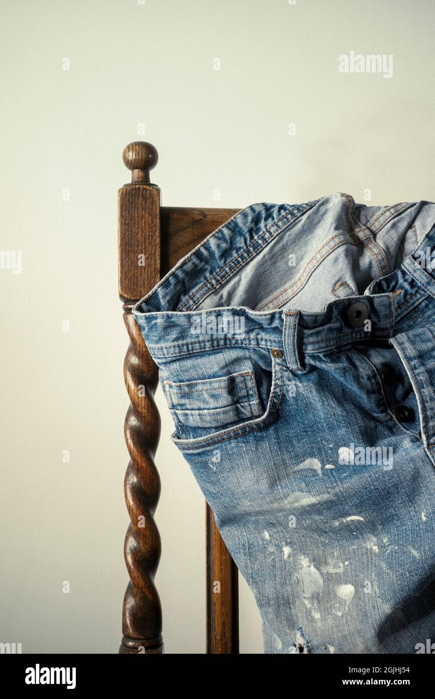 Old denim jeans on a wooden chair. Stock Photo
